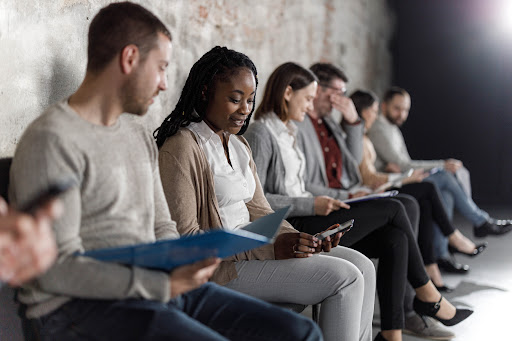 A row of job candidates wait to be interviewed, illustrating the challenge of finding the right hire and the benefits of interim talent