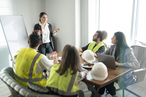 Manager stands in front of a whiteboard while training her contingent workforce, seated at a table