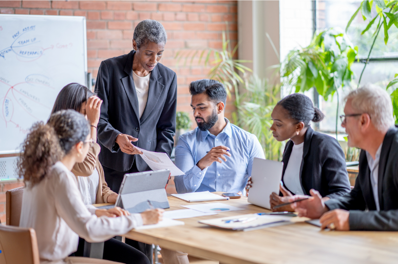 An Fractional Executives s executive meets in a conference room with the leadership team to discuss innovation.